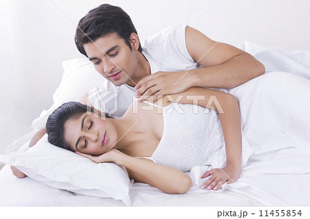Young man looking at woman sleeping in bed Young man looking at woman sleeping in bed 11455854