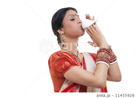 Bengali woman blowing on a conch shell 11455926