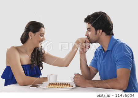 Loving man kissing woman on hand while having coffee against white background 11456004