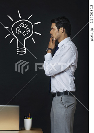 Side view of Indian businessman contemplating on recycling idea at office Side view of Indian businessman contemplating on recycling idea at office 11456312