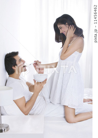 Side view of romantic woman feeding man in bed 11456462