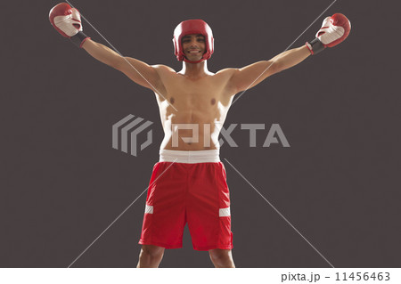 Portrait of an Indian male boxer with arms outstretched celebrating victory isolated over black background 11456463