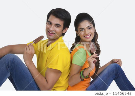 Portrait of beautiful young couple eating ice-cream bars over white background 11456542