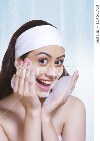 Portrait of cheerful woman washing face against blue background Portrait of cheerful woman washing face against blue background 11456703