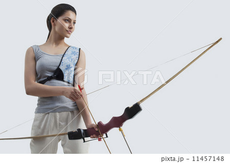 Young female archer with bow and arrow isolated over gray background Young female archer with bow and arrow isolated over gray background 11457148