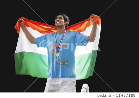 Young hockey player looking up as he holds Indian flag with pride against black background Young hockey player looking up as he holds Indian flag with pride against black background 11457189
