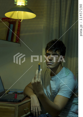 Young male drug addict holding syringe at home Young male drug addict holding syringe at home 11457190