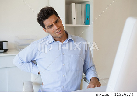 Casual businessman touching his sore back Casual businessman touching his sore back 11526974