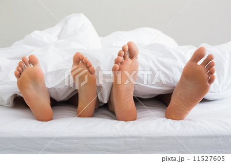 Couples feet sticking out from under duvet 11527605
