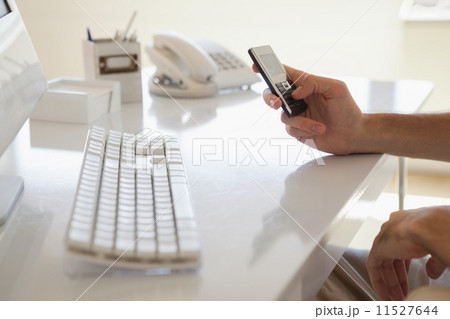 Casual businessman sending a text at his desk 11527644