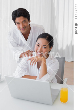 Couple in bathrobes using laptop together in the morning Couple in bathrobes using laptop together in the morning 11527668