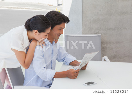 Couple reading a newspaper together Couple reading a newspaper together 11528014
