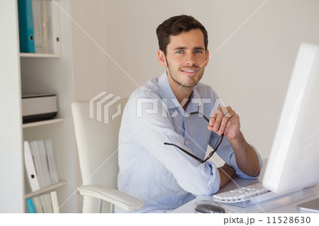 Casual businessman smiling at camera at his desk Casual businessman smiling at camera at his desk 11528630