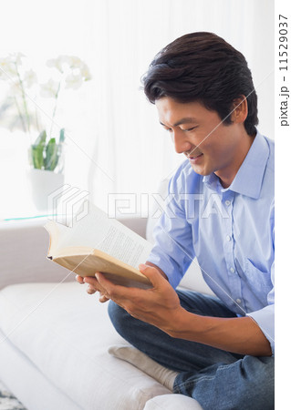 Happy man sitting on couch reading 11529037