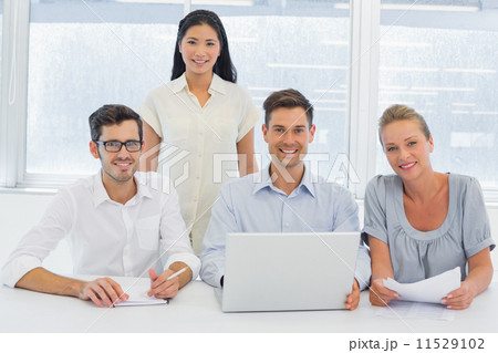 Casual business team working together at desk smiling at camera Casual business team working together at desk smiling at camera 11529102