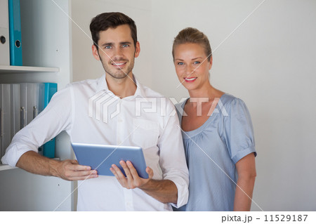 Casual business team smiling at camera man holding tablet 11529187
