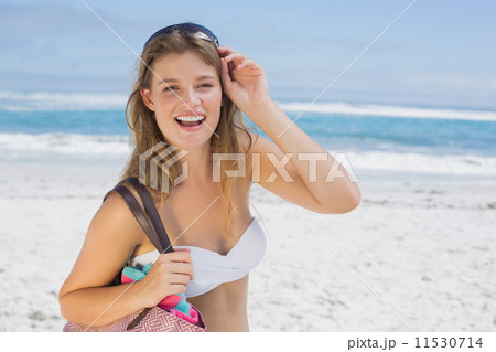 Beautiful smiling blonde on the beach holding bag 11530714