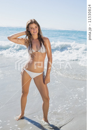 Beautiful smiling woman in white bikini standing on the beach Beautiful smiling woman in white bikini standing on the beach 11530814