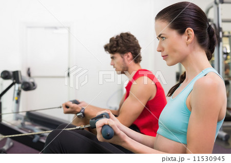 Focused brunette working out on the rowing machine 11530945
