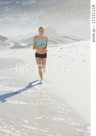 Fit woman jogging on the beach smiling at camera Fit woman jogging on the beach smiling at camera 11531116