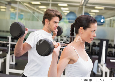Fit couple lifting barbells together Fit couple lifting barbells together 11531117