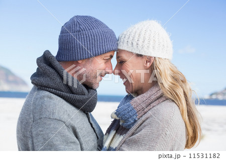 Attractive couple smiling at each other on the beach in warm clo 11531182