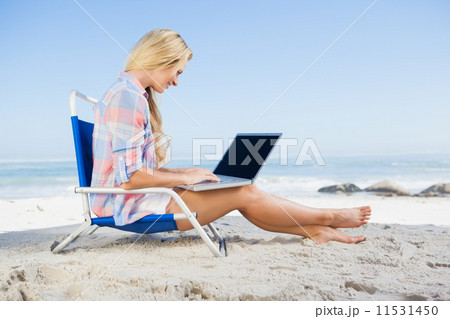 Woman sitting on beach using her laptop Woman sitting on beach using her laptop 11531450