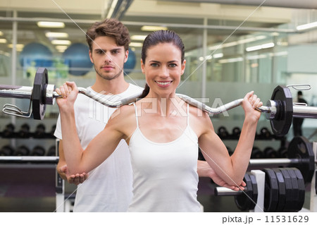 Fit smiling woman lifting barbell with her trainer Fit smiling woman lifting barbell with her trainer 11531629