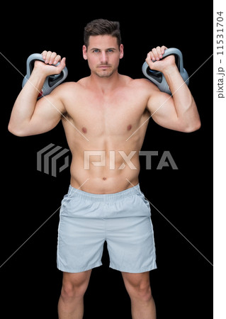 Focused bodybuilder lifting up kettlebells looking at camera Focused bodybuilder lifting up kettlebells looking at camera 11531704