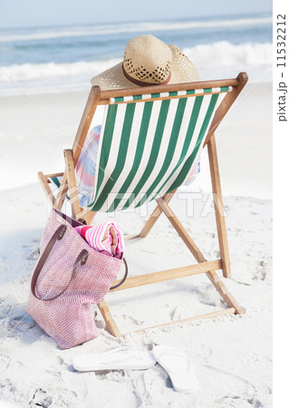 Woman in sunhat sitting on beach in deck chair Woman in sunhat sitting on beach in deck chair 11532212
