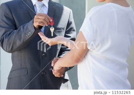 Estate agent giving house key to buyer 11532265