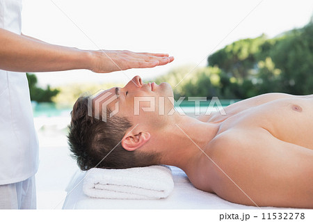 Peaceful man getting reiki treatment poolside 11532278