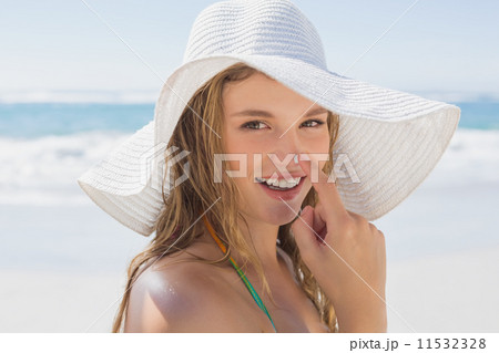 Beautiful girl putting spf on nose on the beach smiling at camer 11532328