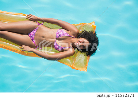 Happy woman lying on lilo in swimming pool 11532371