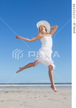 Pretty blonde in white dress leaping on the beach 11532446