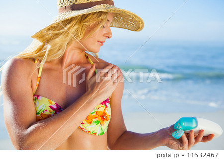 Gorgeous blonde in bikini applying suncream on the beach Gorgeous blonde in bikini applying suncream on the beach 11532467