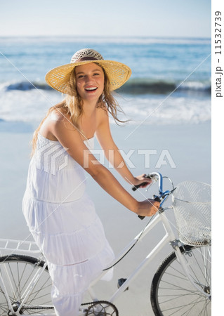 Beautiful blonde in white sundress on bike ride at the beach 11532739