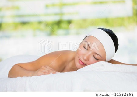 Smiling brunette lying on massage table with eyes closed 11532868