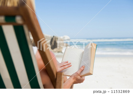 Woman sitting in deck chair at the beach reading 11532869