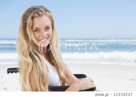 Wheelchair bound blonde smiling at the camera on the beach 11533237