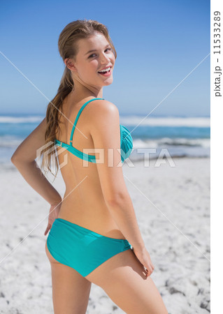 Fit woman in bikini standing on the beach smiling at camera Fit woman in bikini standing on the beach smiling at camera 11533289