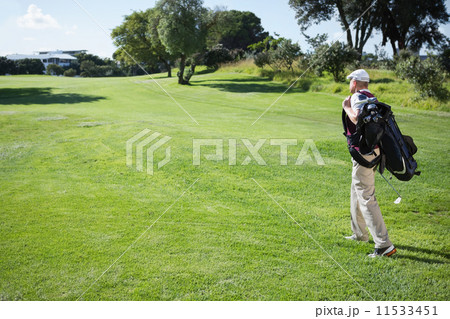 Golf player carrying his bag and walking 11533451
