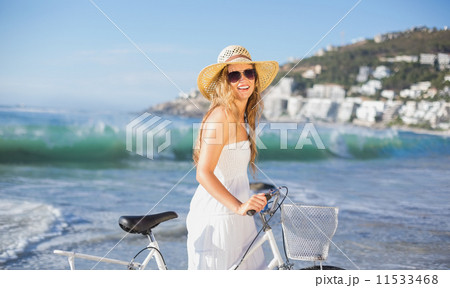 Beautiful smiling blonde in sundress with her bike at the beach 11533468