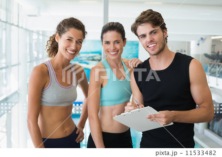 Fit women with trainer taking notes and smiling at camera 11533482