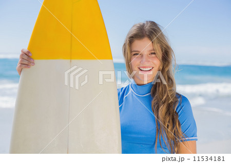 Fit smiling surfer girl on the beach with her surfboard 11534181
