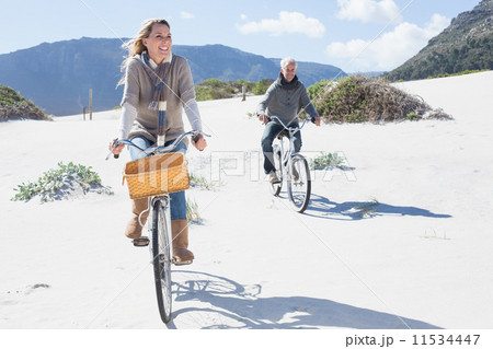 Carefree couple going on a bike ride on the beach Carefree couple going on a bike ride on the beach 11534447