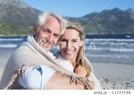 Smiling couple sitting on the beach under blanket Smiling couple sitting on the beach under blanket 11534598