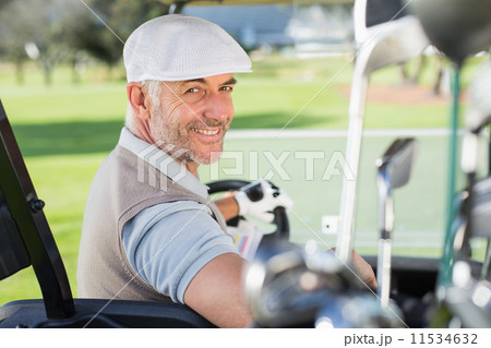 Happy golfer driving his golf buggy smiling at camera Happy golfer driving his golf buggy smiling at camera 11534632