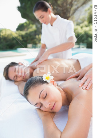 Attractive couple enjoying couples massage poolside Attractive couple enjoying couples massage poolside 11534778