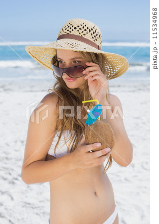 Pretty blonde in white bikini holding coconut drink on the beach Pretty blonde in white bikini holding coconut drink on the beach 11534968